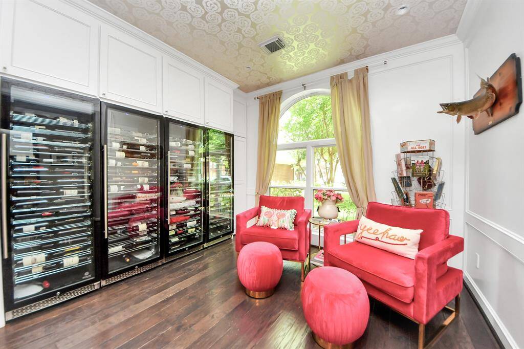 ***Wine Cooler towers can be removed**A show-stopping wine room designed for the enthusiast! This custom space boasts multiple temperature-controlled wine fridges, built-in cabinetry, and elegant crown molding. Relax in the stylish seating area with a large arched window offering serene views and plenty of natural light.