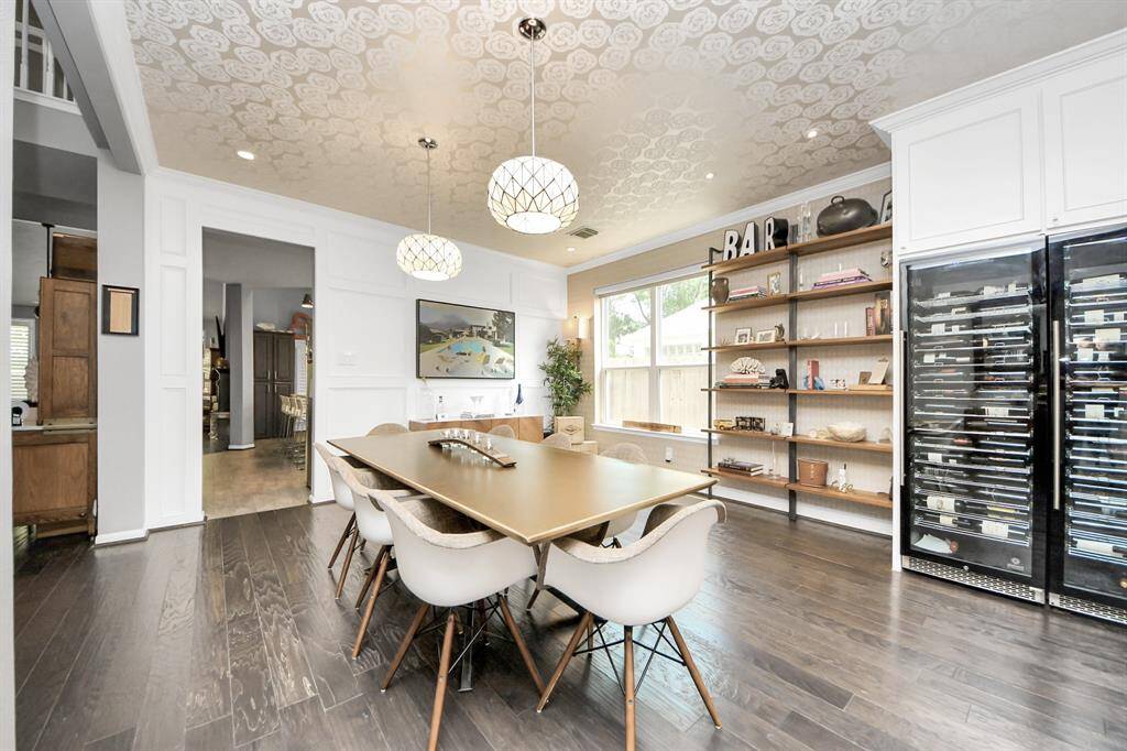 Enjoy elegant gatherings in this stylish dining room with statement lighting, wall molding, and a stunning floral-patterned ceiling. The built-in shelving and full wine fridge wall complete the upscale ambiance, making this space perfect for entertaining.