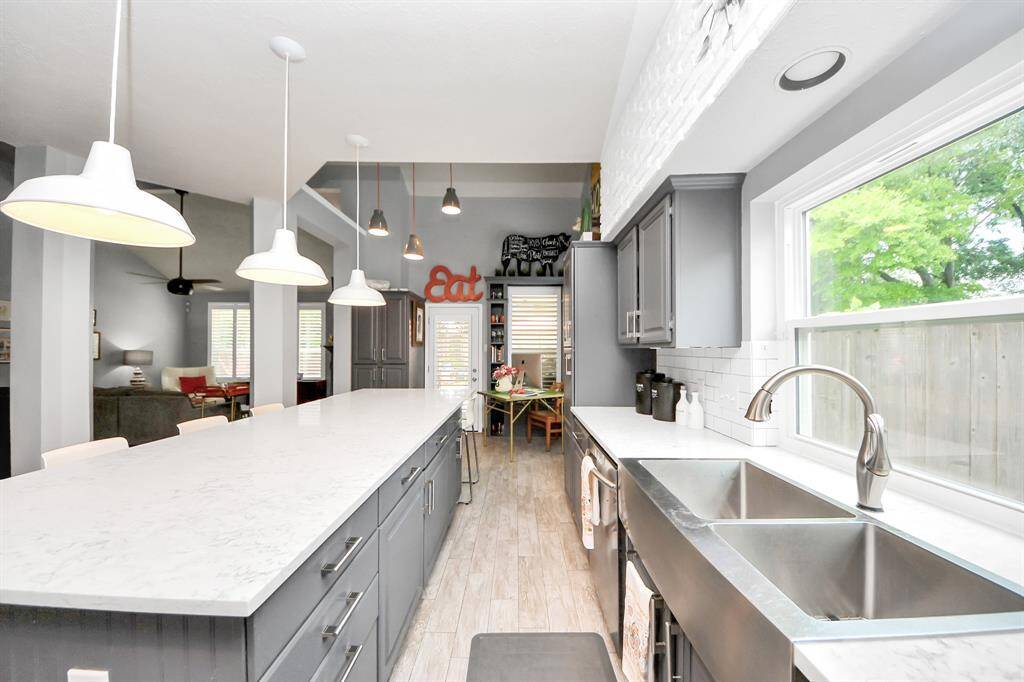 Cook and entertain with ease in this sleek kitchen with dual-basin stainless steel sink, wall-to-wall cabinetry, and scenic views of the backyard. The space balances style and functionality for everyday living or hosting guests.
