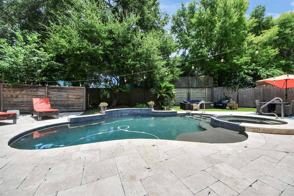 A beautifully designed pool with attached spa and waterfall feature takes center stage in this tranquil backyard oasis. Surrounded by manicured greenery, this is your private retreat.