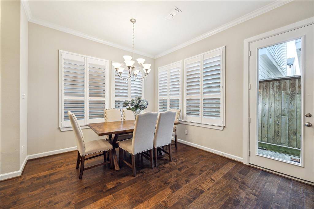 Gather and enjoy meals in this light-filled dining nook, framed by elegant plantation shutters and warm hardwood floors—an inviting space for everyday dining or special occasions.