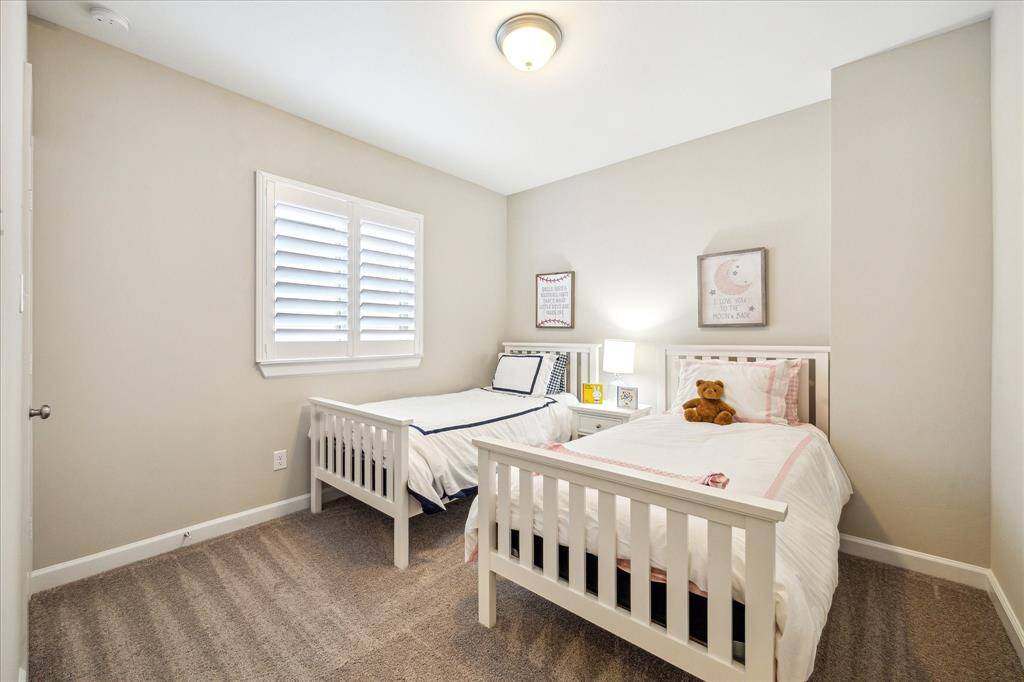 This cheerful secondary bedroom is perfect for kids or guests, offering soft carpet, neutral tones, and plantation shutters for added privacy and charm.