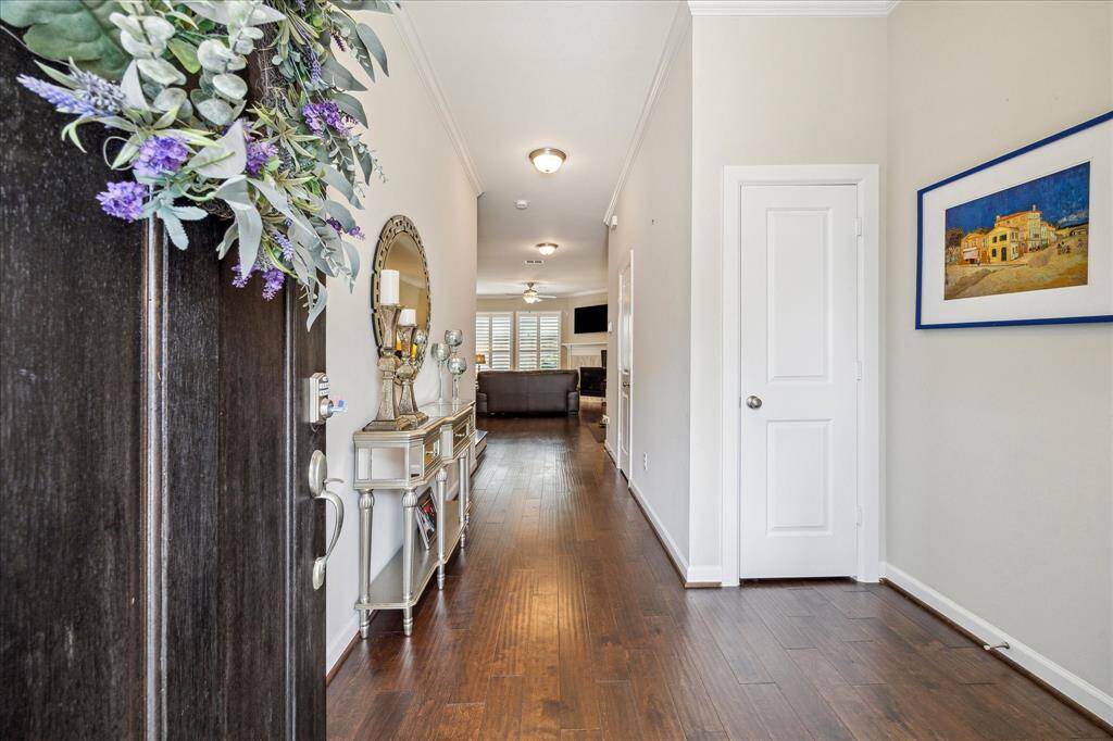 Welcome home to a warm and inviting entryway featuring rich hardwood floors, crown molding, and a convenient hall closet—perfect for coats, bags, or extra storage—all leading into the bright, open living space beyond.
