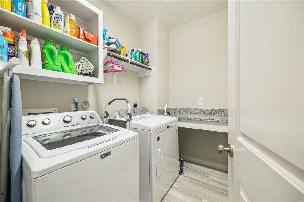 Conveniently located on the same floor as all bedrooms, this spacious laundry room offers built-in shelving, folding space, and plenty of storage to keep laundry day organized and efficient.