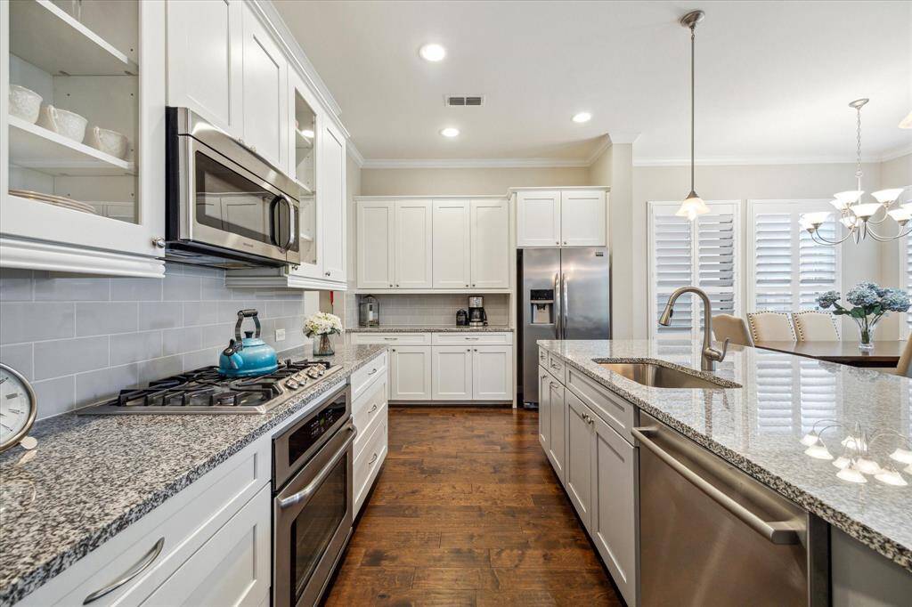 Sleek granite counters, under-cabinet lighting, and stainless appliances bring function and flair to this thoughtfully designed culinary space.