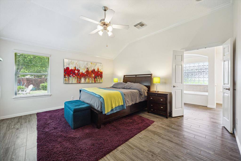 The serene primary suite offers a relaxing retreat with crown molding, natural light, and direct access to the spa-like bath.
