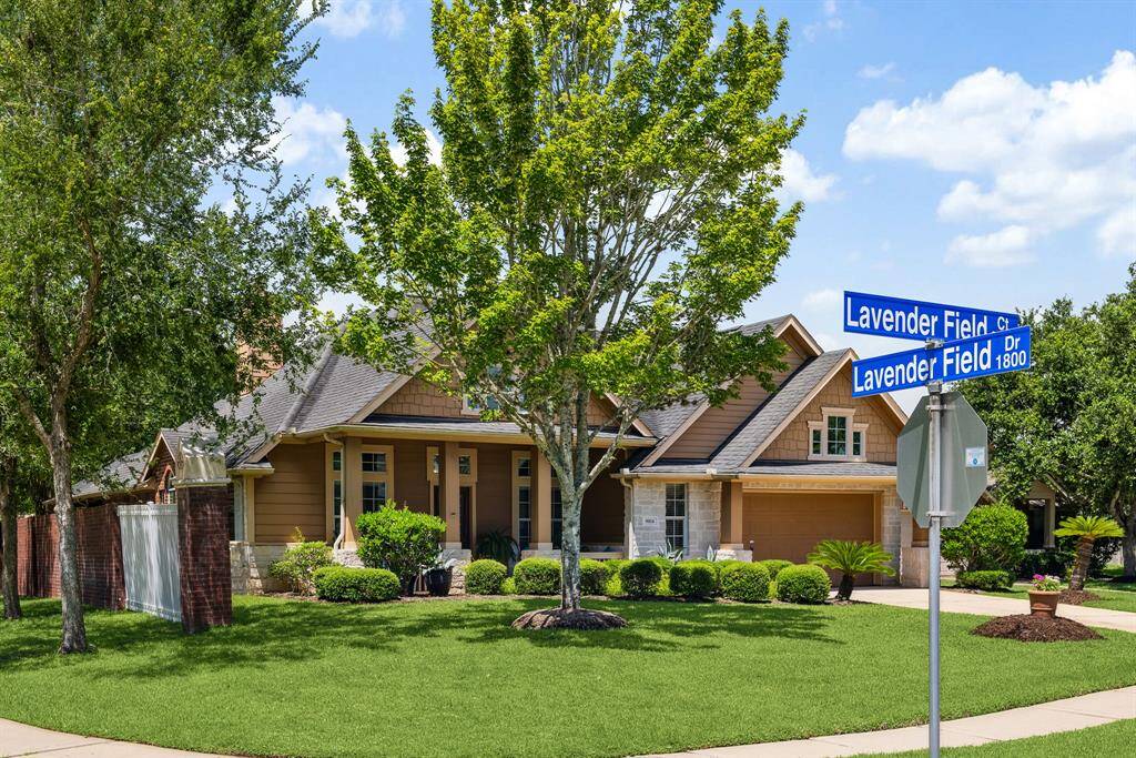 Mature trees and manicured hedges frame this corner-lot gem with timeless exterior design.