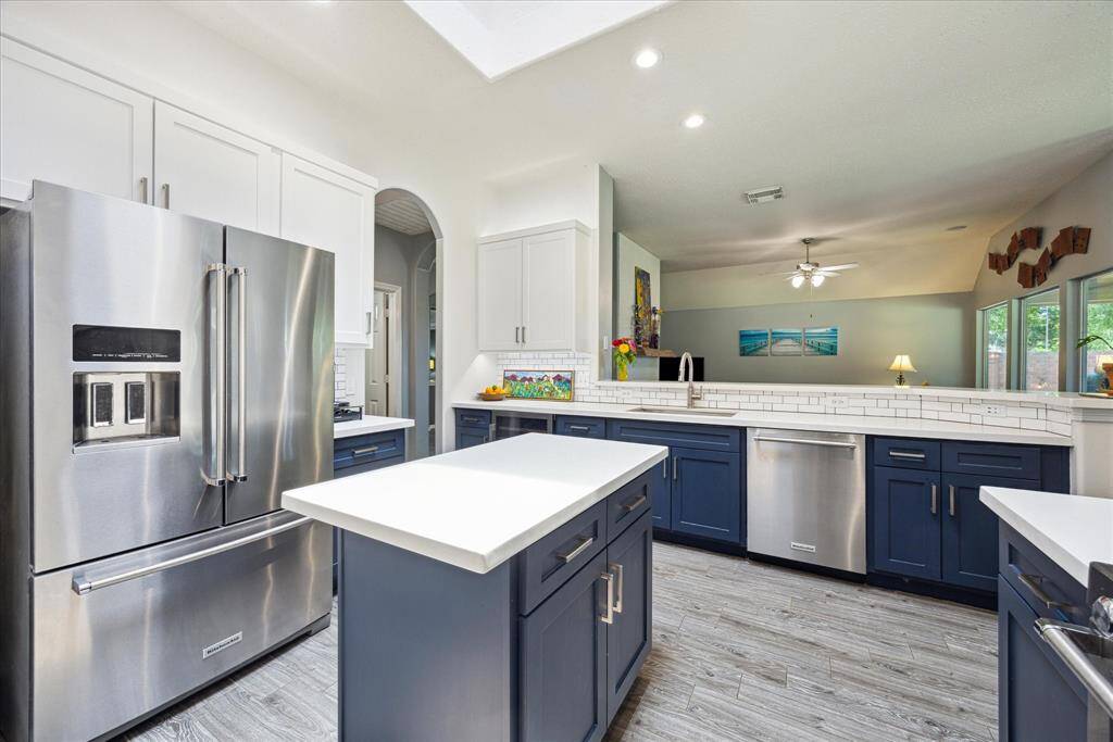 The sleek island adds prep space and functionality, while under-cabinet lighting highlights the clean lines of the updated design. Both the refrigerator and the built-in wine fridge next to the sink will stay with the home.