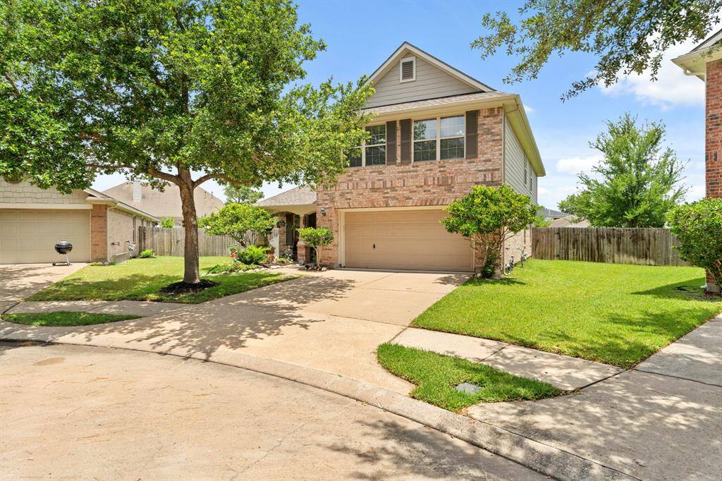 Charming two-story brick home with a spacious driveway and attached garage.