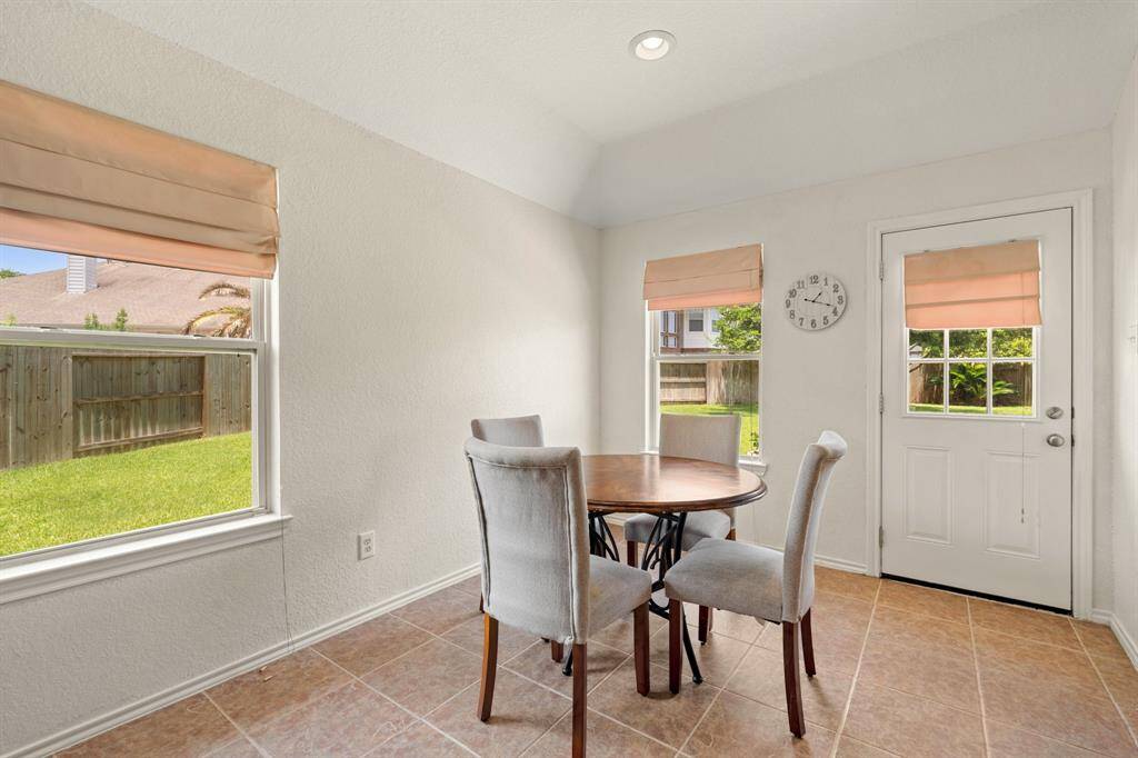 This bright dining area features tile flooring and large windows offer views of the fenced backyard.