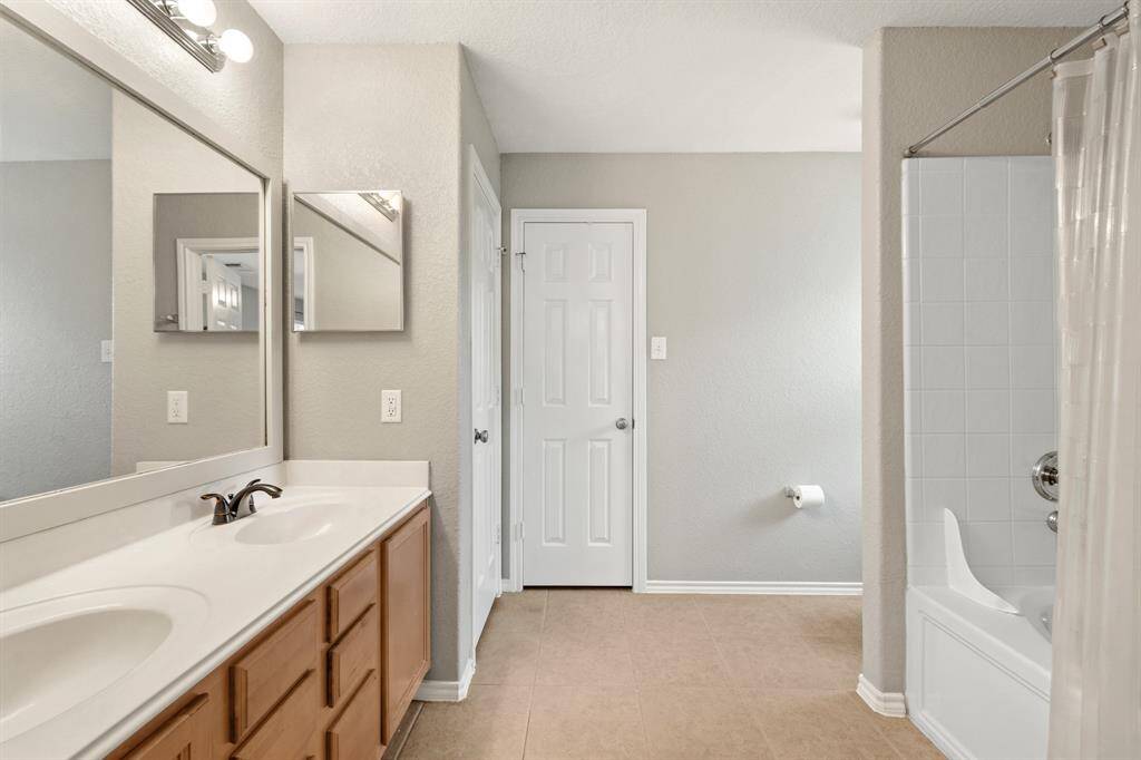 Primary bathroom features a double vanity with ample storage, modern lighting, and a neutral color palette.