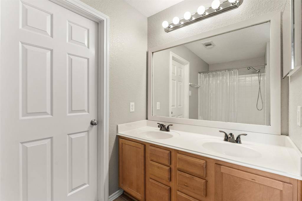 Spacious bath layout with a double vanity, large mirror, and Hollywood lighting.