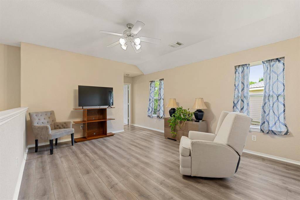 Upstairs bright and spacious loft area with light wood-styled flooring, neutral walls, and a ceiling fan.