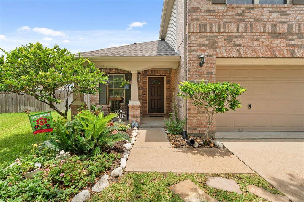 Cozy entrance, a two-car garage, and lush greenery for added curb appeal.