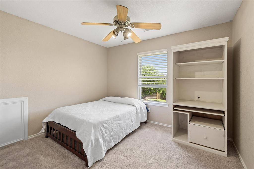 Second bedroom upstairs with neutral walls, carpet flooring, and a ceiling fan.