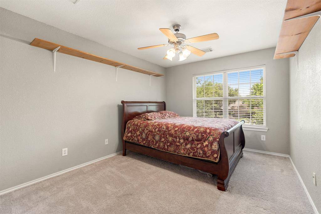 Cozy third bedroom with neutral walls, carpet flooring, and a ceiling fan.