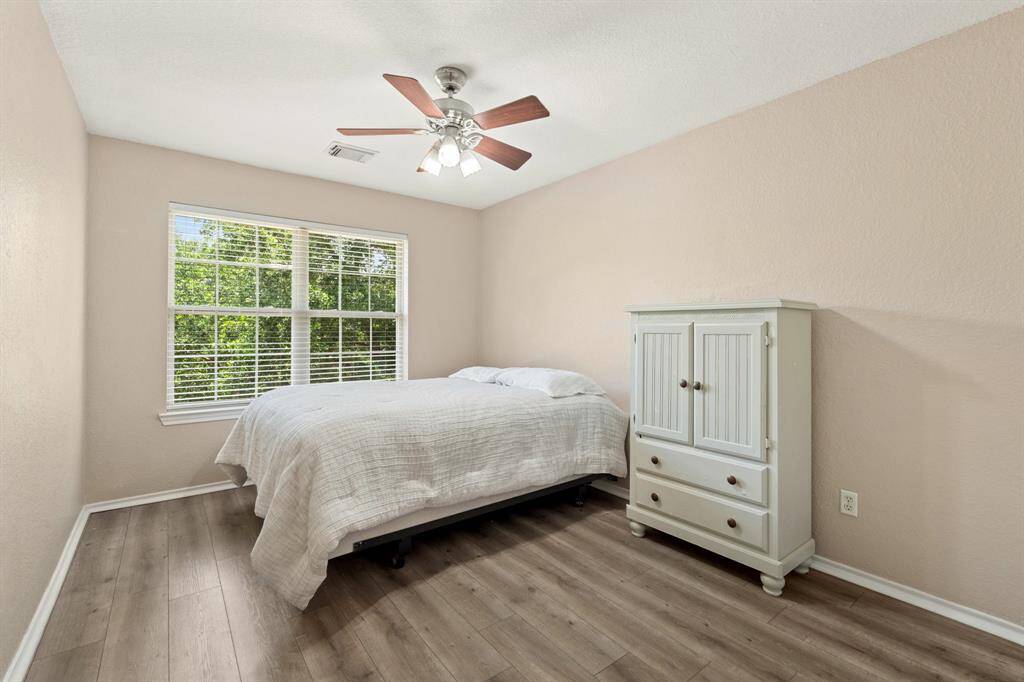 Fourth bedroom bedroom features a cozy layout with neutral walls, wood-styled flooring, and ample natural light from a large window.