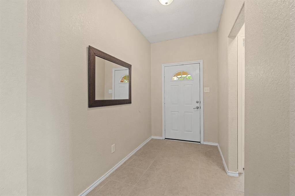 Neutral walls and tiled flooring lead into the living area space.