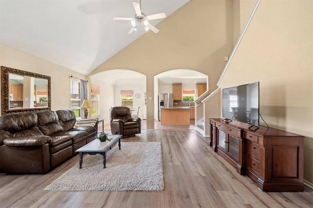 This spacious living room features high vaulted ceilings, a ceiling fan, and abundant natural light.