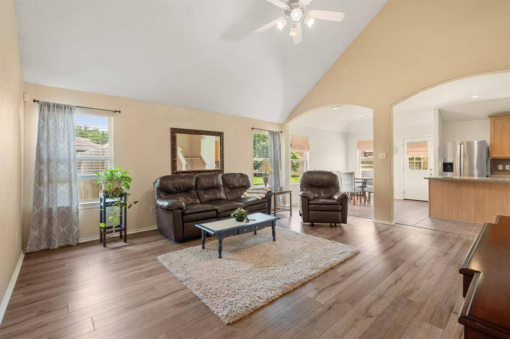 The living room opens to a modern kitchen with stainless steel appliances and a dining area.