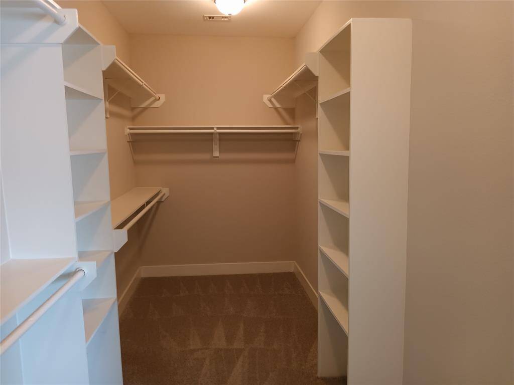 Another photo of the primary walk-in closet with built in shelves.