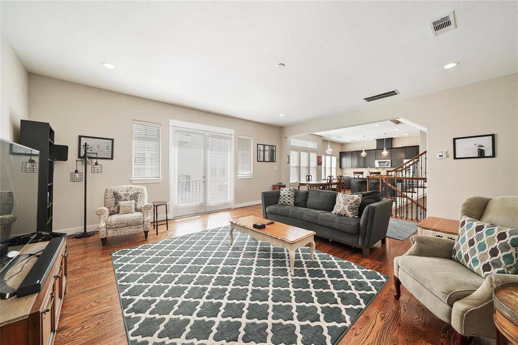 Staged.  Spacious living room with beautiful hardwood floors, french doors open onto the balcony and tons of natural light.  Open living, dining and kitchen concept for entertaining and family gatherings.