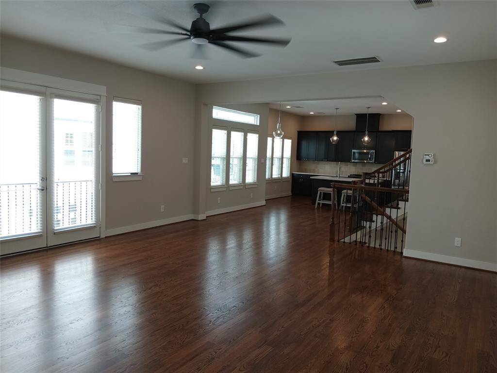 View of the living room to the dining room and the island kitchen.  Double doors open onto the second floor balcony.  Beautiful hardwood floors.
