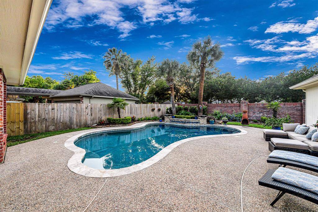 TRAVERTINE COPING SURROUNDS THIS POOL WITH DRAMATIC WATERFALL AND FIRE FEATURES WITH RECENTLY RENOVATED AND REPLASTERED PEBBLE TEC POOL SURFACE