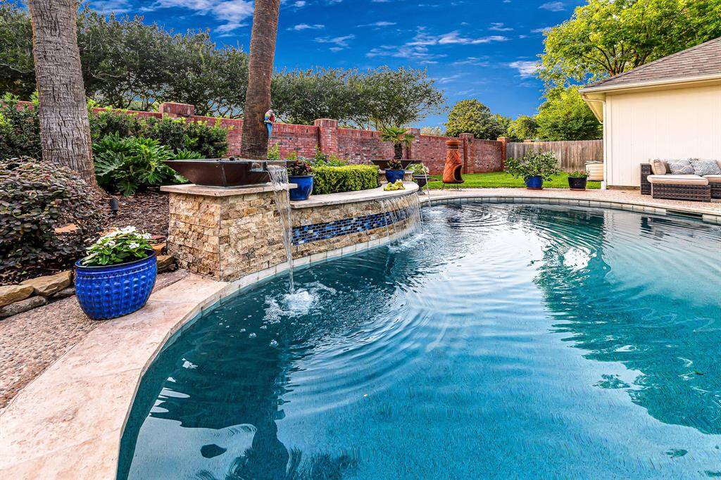 CUSTOM BUILT WATERFALL WITH ACCENT MEDITERRANEAN BLUE TILE HIGHLIGHTS THIS RESORT STYLE POOL