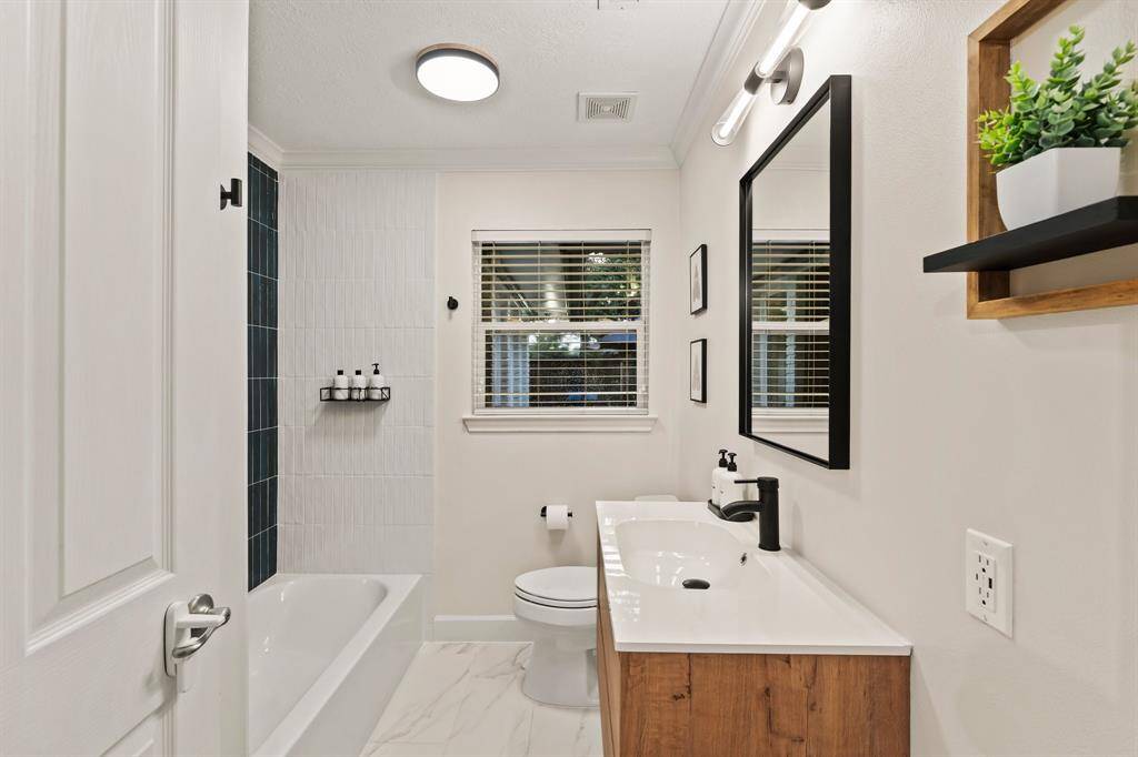 Updated hall bathroom on first floor with modern floating vanity, custom lighting and shower tile that pops!