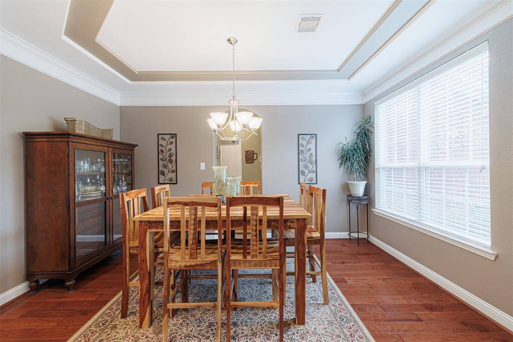 Formal dining room with tray ceiling, crown molding and wood flooring.