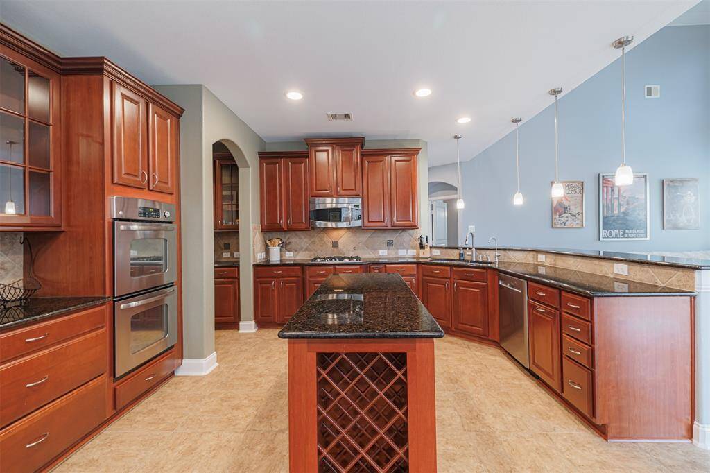 The open-concept kitchen offers an island w/wine rack, recessed and pendant lighting, stainless steel appliances and breakfast bar.