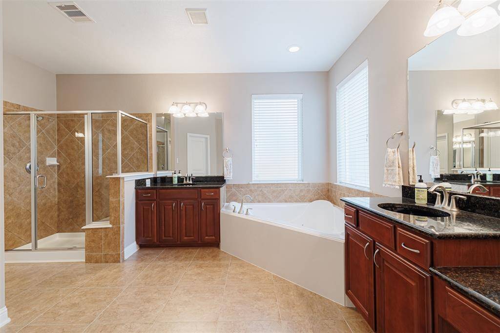 Spa-like primary ensuite bath with double vanities, separate walk-in shower and large jetted tub.