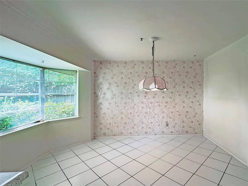 This breakfast room features a cozy dining area with a large bay window. The Large Bay windows offer plenty of natural light, and the white tiled floor adds a clean, spacious feel.
