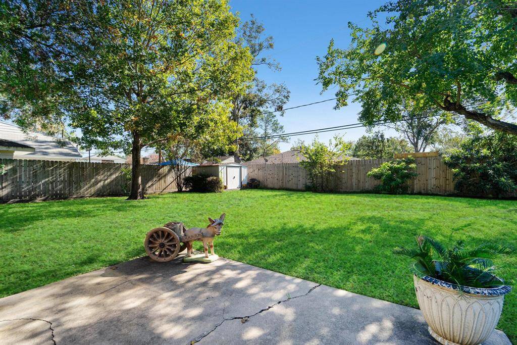 This photo showcases a spacious, fenced backyard offering ample space for outdoor activities. A small shed provides extra storage, and a concrete patio is perfect for relaxation or entertaining.