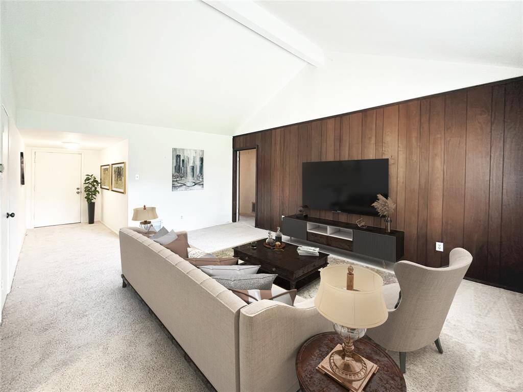 This living room features a high vaulted ceiling, fresh carpet throughout, and a dark wood accent wall.  The floor plan offers plenty of space for a adequate seating / furnishings arrangement providing a comfy lifestyle and welcoming atmosphere.  Image is Virtually Staged.