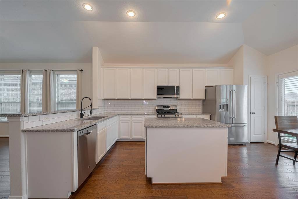 The kitchen is equipped with a full suite of stainless steel appliances, including a LG microwave (2022), a GE dishwasher, a GE stove, and a KitchenAid refrigerator. These modern appliances not only enhance functionality but also add a sleek, contemporary look to the space.