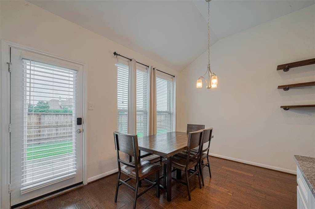 Breakfast area with large windows overlooking backyard and pendant light.
