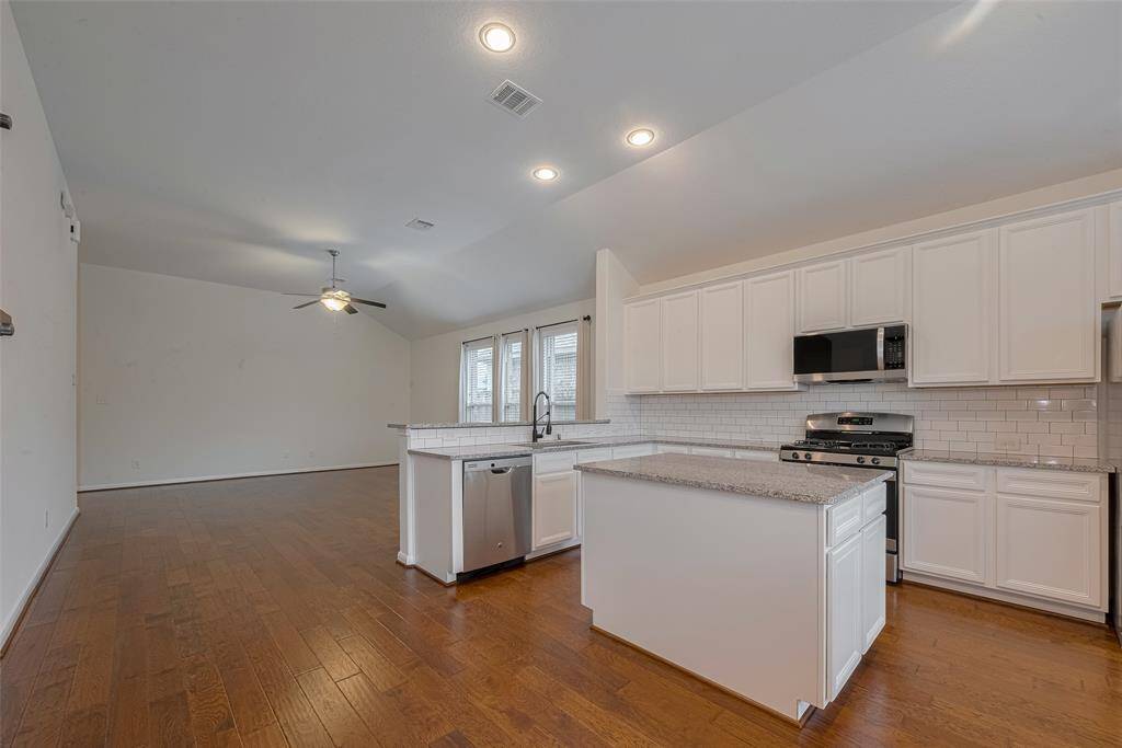 The kitchen includes a functional island with built-in storage, perfect for meal prep and additional organization. A single basin undermount sink is paired with a modern faucet with sprayer (2023).