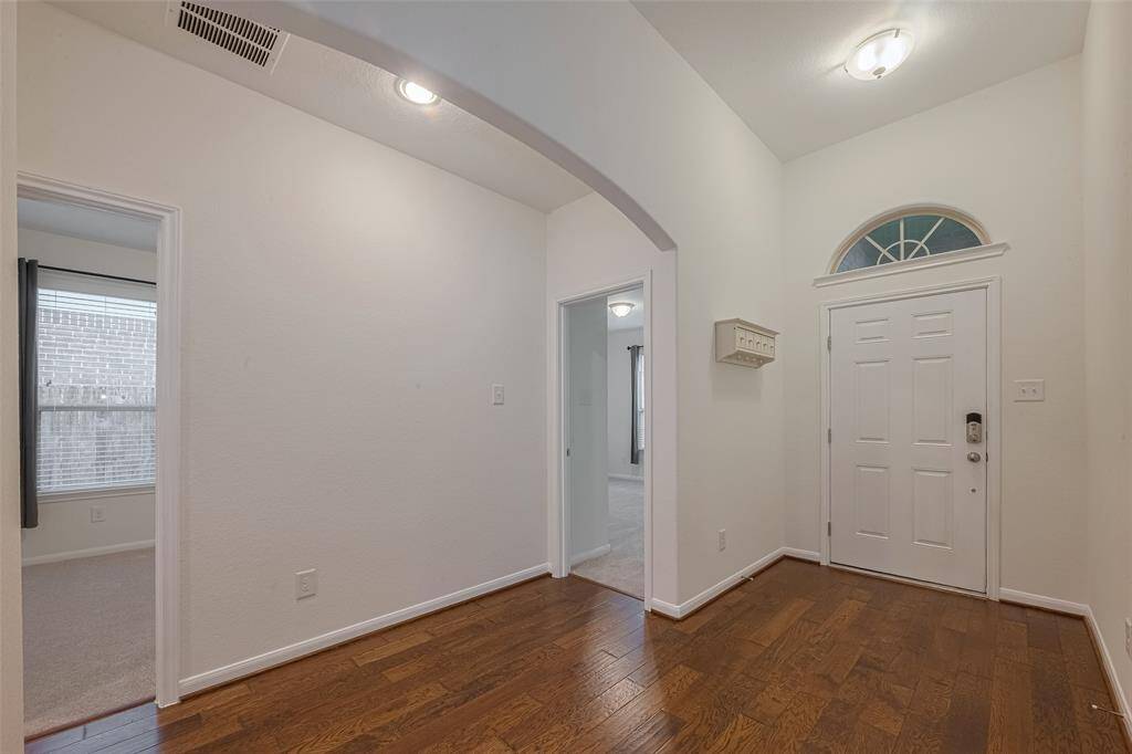 This inviting entryway measures 5'5" x 5'10" and features distressed hardwood floors that add warmth and character, complemented by brushed nickel door hardware for a modern touch. A dome ceiling light provides soft, ambient illumination. The entry is equipped with a keyless entry system, blending convenience with contemporary design.