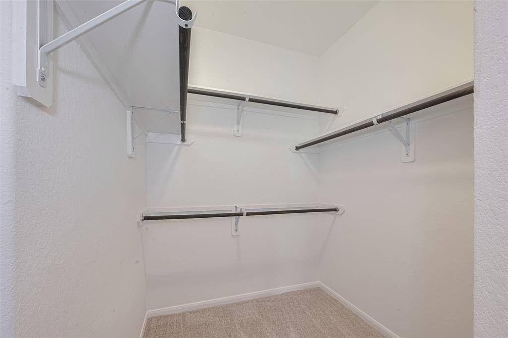 5’8”x9’11” walk-in closet with built-in shelving, hanging racks, and carpet.