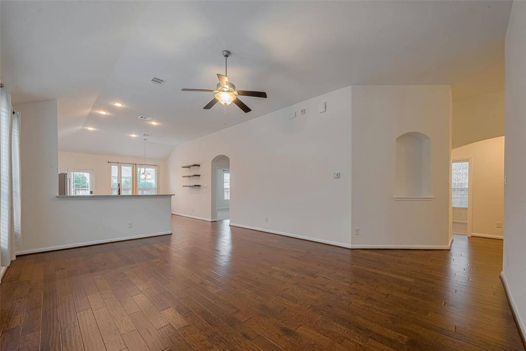 This home features an open floorplan that seamlessly connects the family room and kitchen, creating a spacious and inviting atmosphere ideal for entertaining or everyday living. A hallway off the main living area leads to the secondary bedrooms and a full bathroom, offering privacy and a functional layout.