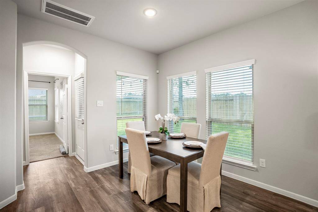 Framed by three large windows overlooking the backyard, the breakfast room is bright and welcoming—perfect for slow mornings or dinner with a view. The arched entry leads to the private primary suite, while the back door just beside it opens onto the covered patio and extended yard. Everything flows right where you want it to.