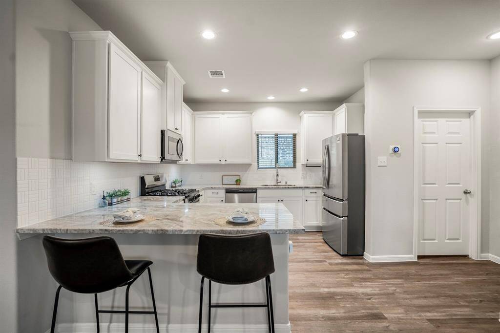This kitchen doesn’t just look good—it works hard, too. Stainless appliances (yes, the fridge stays!), rows of cabinetry, and granite counters make the space as functional as it is stylish. To the right of the fridge, the door leads to a separate laundry room—washer and dryer included—and just out of view is a walk-in pantry for even more storage. Don’t miss the Kohler kitchen faucet and Nest thermostat—two smart upgrades that raise the bar on comfort and convenience.