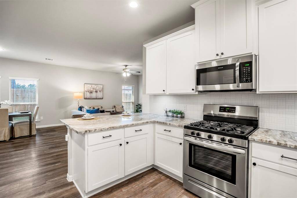 The heart of this kitchen—your gas range and built-in microwave—sits front and center with a modern geometric tile backsplash and generous counter space on both sides. Whether you're whipping up a weeknight dinner or meal prepping for the week, you’re right in the middle of it all. And don't miss the deep drawers and extra storage in the peninsula—function meets form.