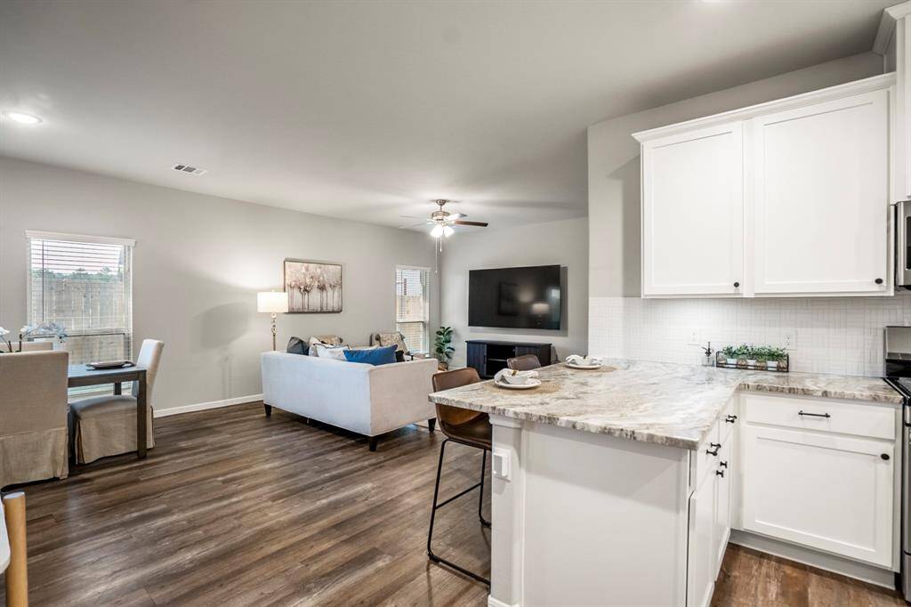 Standing at the kitchen peninsula, this is your everyday view—open, connected, and filled with natural light. Whether you're serving breakfast at the bar, chatting with guests in the living room, or watching the backyard through the dining windows, everything flows together beautifully in this main living space.