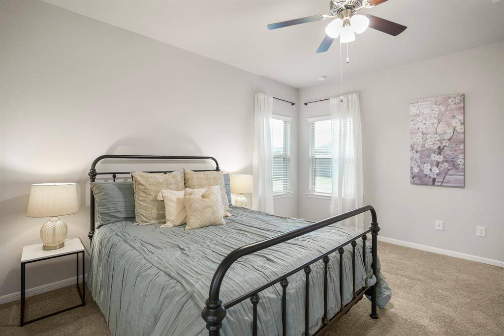 This view from the en suite bath highlights just how much natural light the primary bedroom enjoys, thanks to its dual rear-facing windows. Tucked at the back of the home, it offers a quiet retreat from the rest of the floor plan—calm, cozy, and just steps from your morning routine.