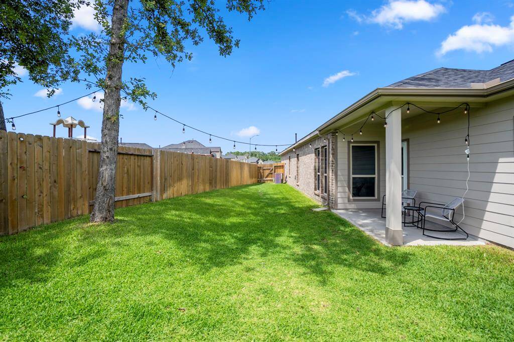 From this angle, you can really take in the spacious sideyard—and spot the park just beyond the side fence. Mature trees offer rare shade for a newer build, and thoughtful upgrades like the full gutter system and soft-start A/C unit (visible in the distance) add comfort and efficiency where it counts.