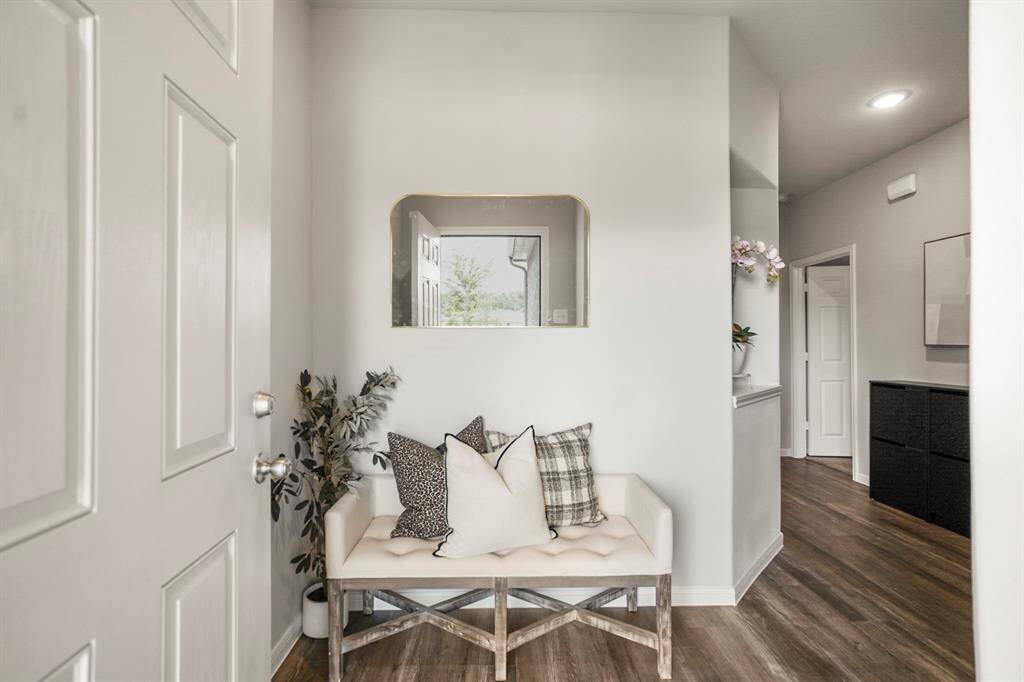 Step inside and you're greeted by clean lines, a recessed display shelf, and durable vinyl plank flooring that flows seamlessly throughout the home. The angled wall adds subtle character, while the hallway to the right leads you toward the main living areas—with both secondary bedrooms and a full bath tucked thoughtfully along the way.