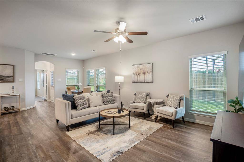 The main living area is open, inviting, and anchored by natural light from the wall of windows overlooking the backyard. Tucked in the back corner behind the sofa is the breakfast room—just steps from the kitchen for easy everyday flow. Through the arched doorway at the rear, you’ll find the private primary suite and access to the covered back patio.